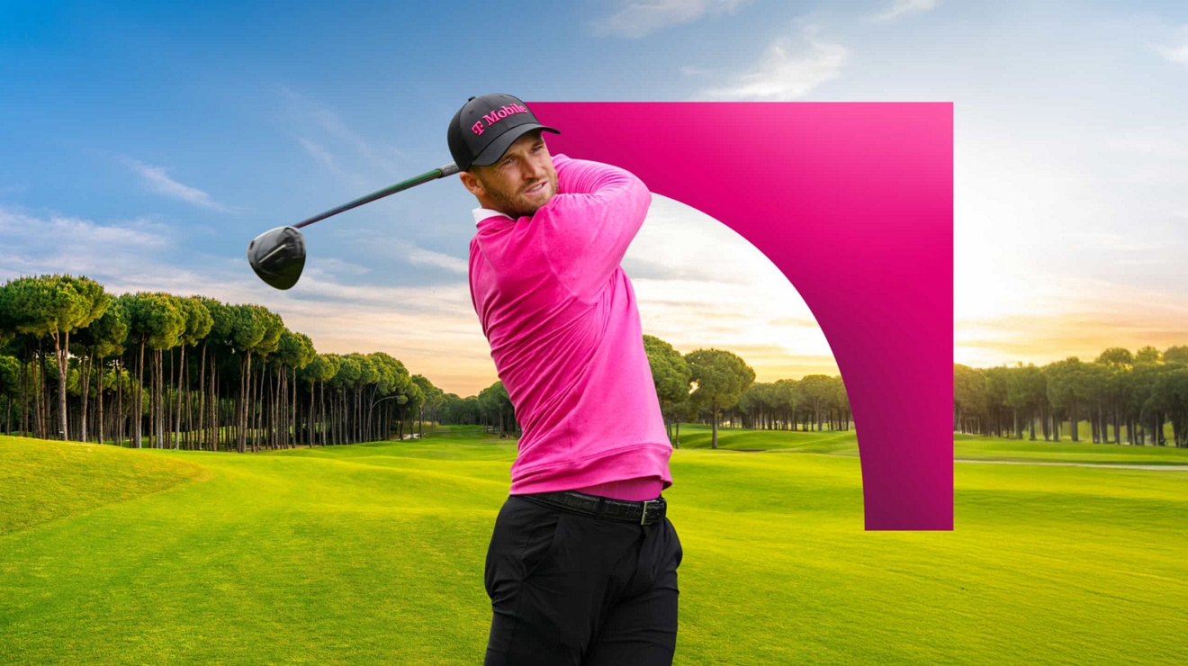 A PGA golfer in T-Mobile hat and shirt finishes a golf swing and tracks the ball as it lands.