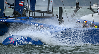 The USA sailing team racing at SailGP on a blue catamaran with the T-Mobile for Business logo.