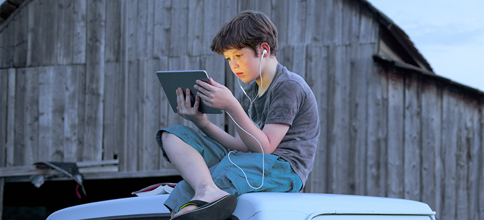 Boy sitting on top of truck looking at screen
