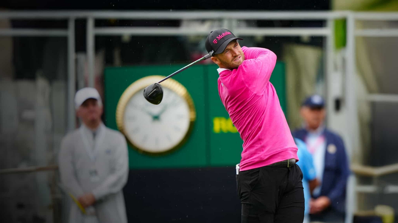 A PGA golfer in T-Mobile hat and shirt finishes a golf swing and tracks the ball as it lands