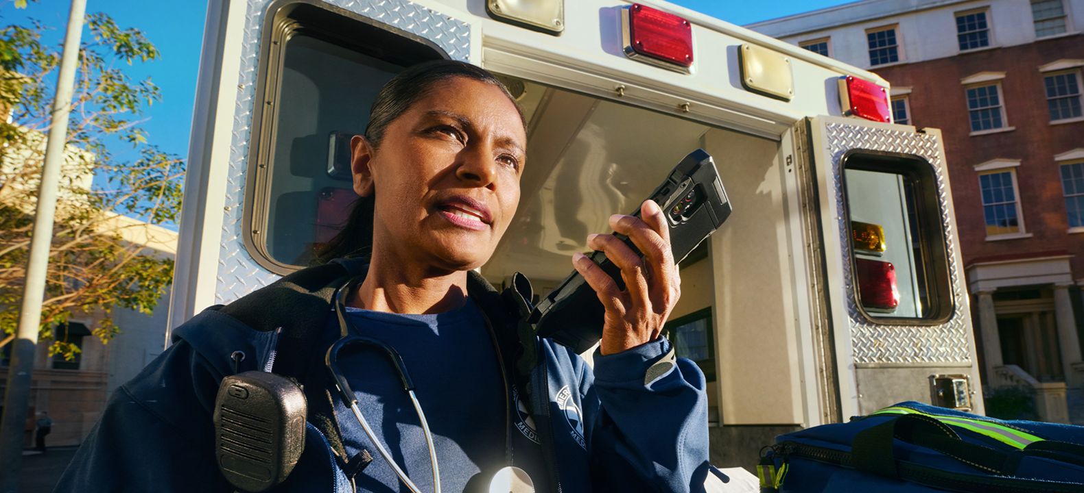 First responder taking a phone call beside a service vehicle. 