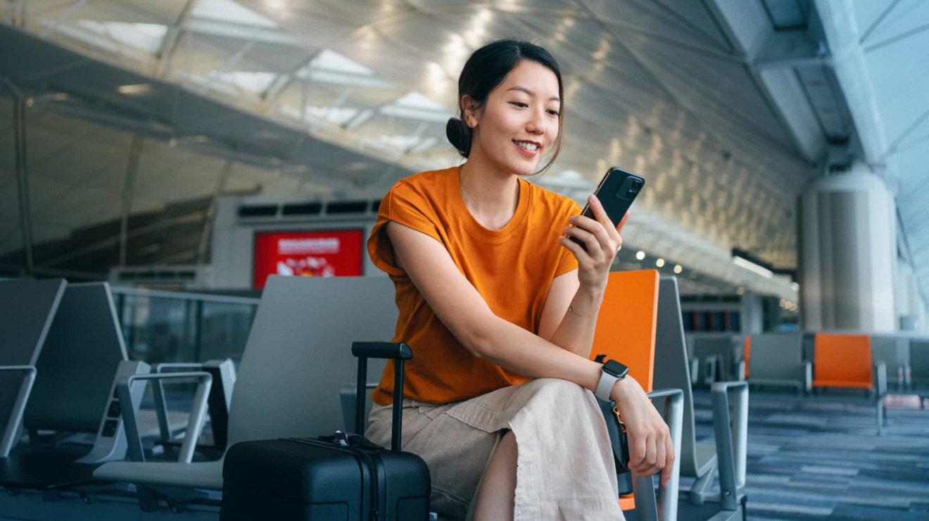 A business traveler in an airport lounge uses their secure mobile device to connect with the office.
