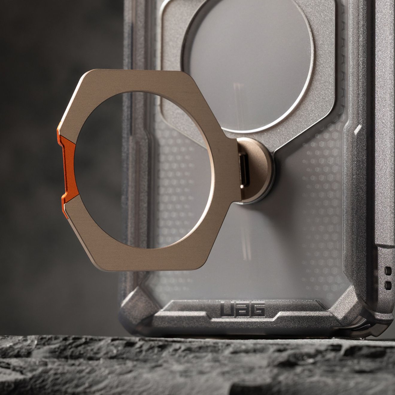 Close-up of a rugged UAG phone case featuring a metallic ring stand extended from the back.