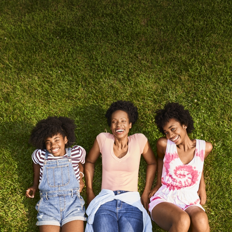 Three women laying in the grass smiling