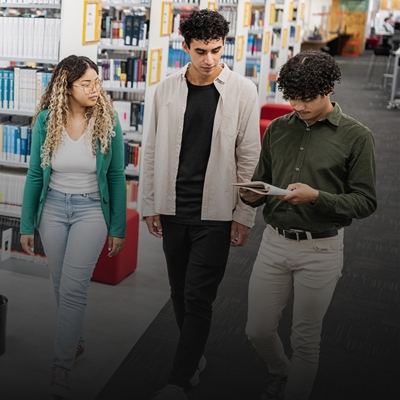 Three friends walking through a library.