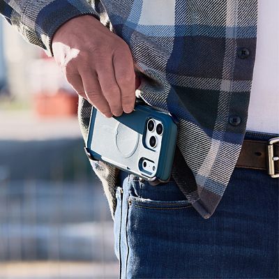 A person wearing a blue plaid shirt holds a silver iPhone 17 Pro in a blue ZAGG Teton protective case at their hip.