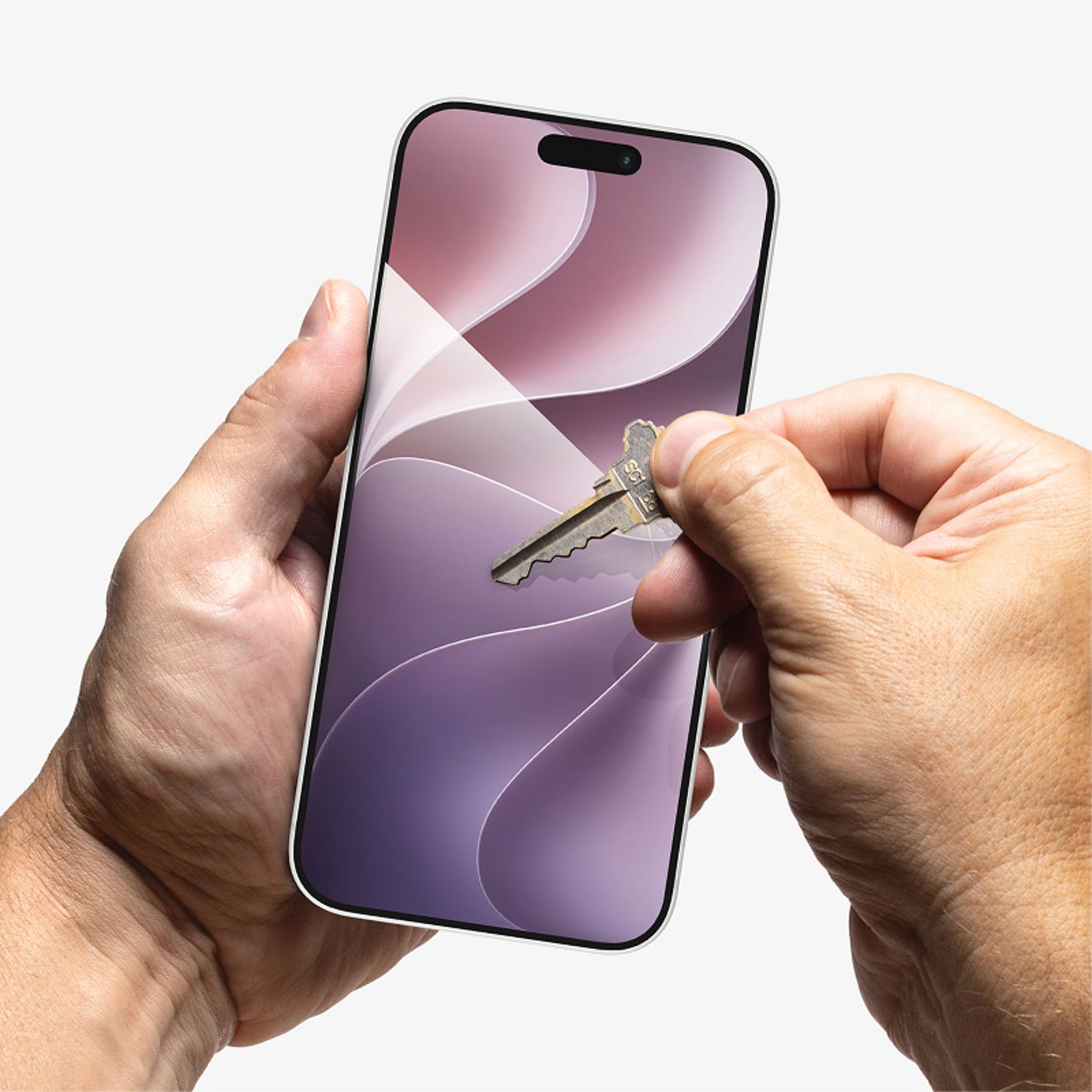 A hand holds an iPhone while a metal key is pressed against the screen protected by ZAGG XTR4 tempered glass, demonstrating scratch resistance.