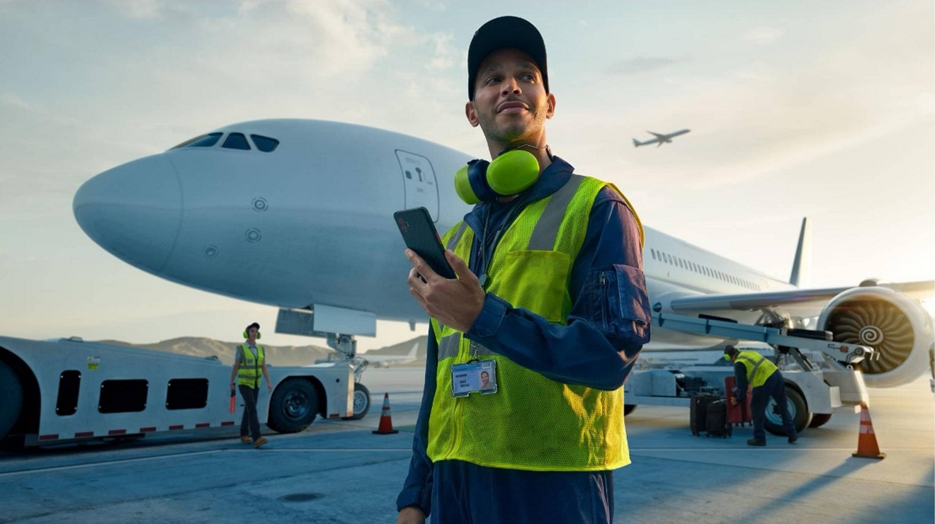 An airline maintenance tech provides a status update from an airport tarmac on a smartphone.