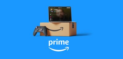 Una laptop con el programa de Amazon Prime The Boys en pantalla, apilada encima de una caja, con un mando de juegos y auriculares al lado de la caja.