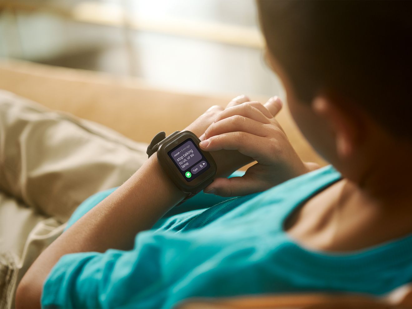 A young boy is looking at his smart watch.