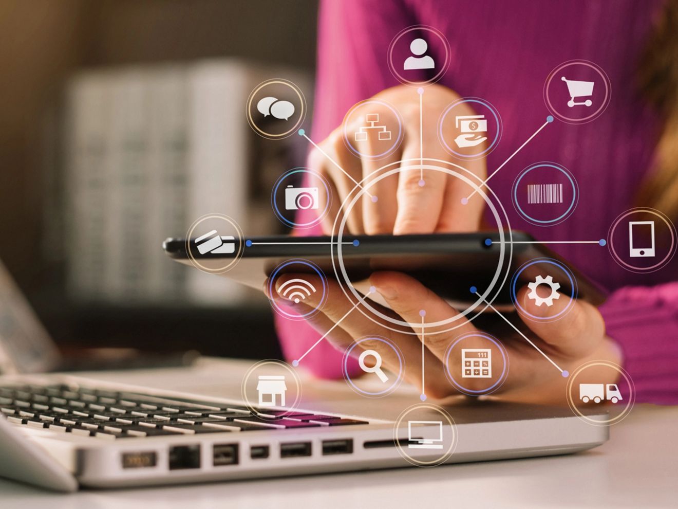 A person is using a smartphone beside a laptop with connectivity icons displayed over the smartphone.