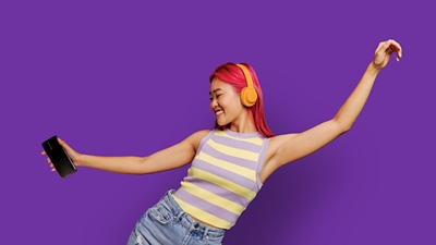 Woman dancing with her phone and wearing headphones. 