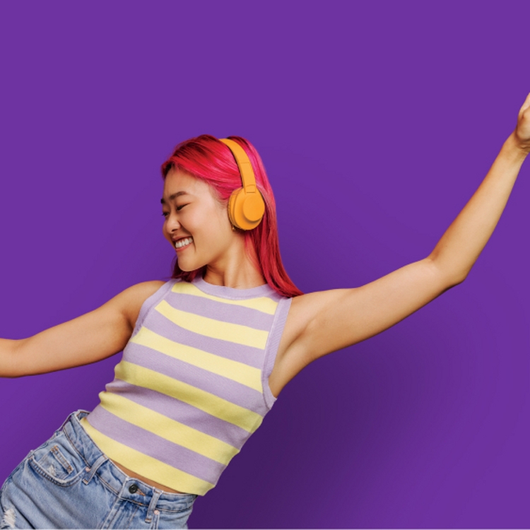 Mujer bailando con su teléfono mientras usa auriculares.