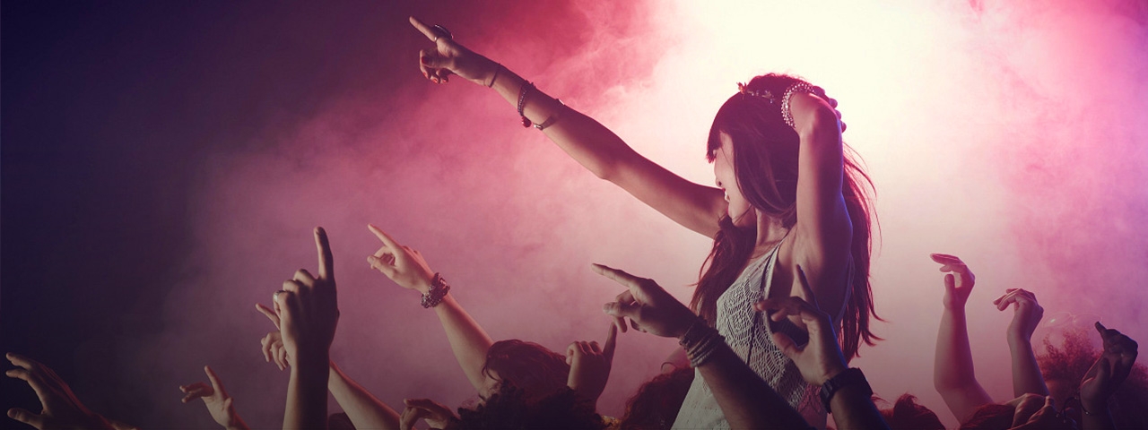 A woman sings along with the music while sitting on another person’s shoulders at a live concert.