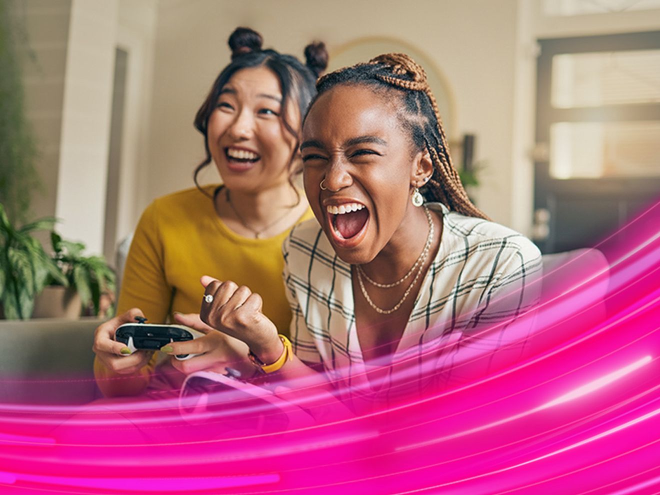 Two women are sitting on a couch playing video games.