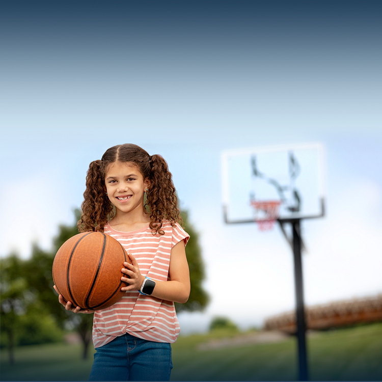 Una niña sonriendo, usando un reloj SyncUP KIDS y jugando al básquet.