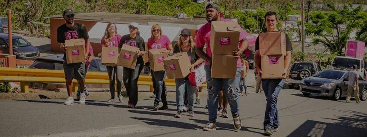 Voluntarios empleados de T-Mobile llevando cajas de cartón