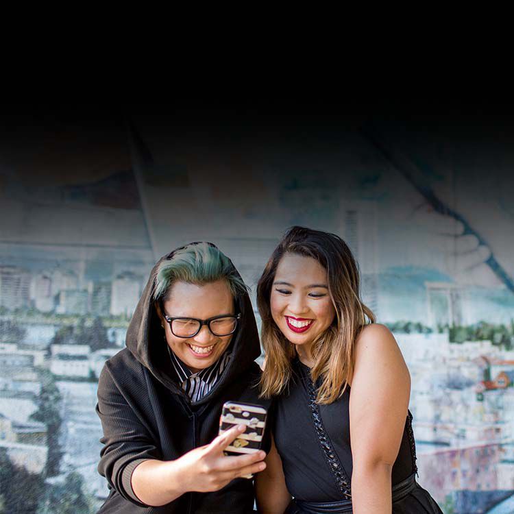 Two women smiling while looking at a cell phone