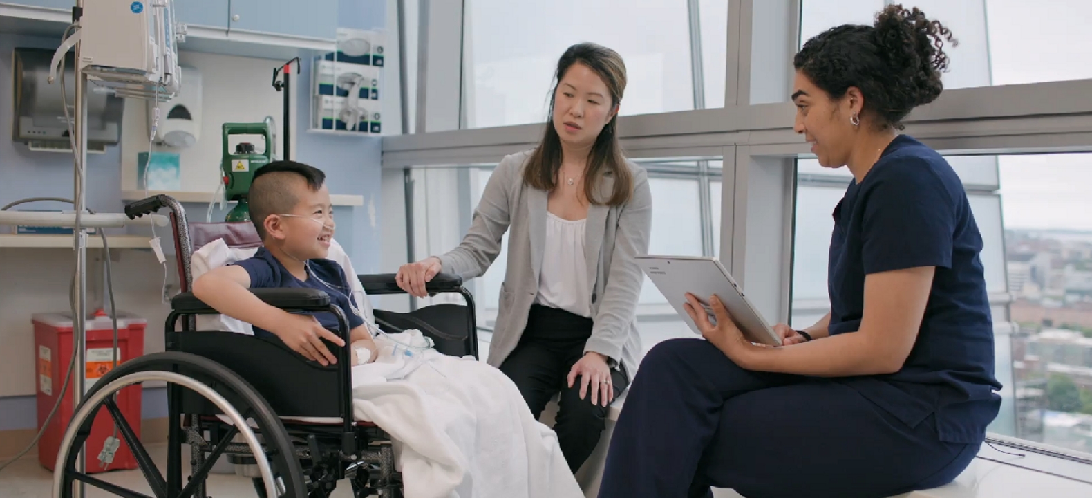 A young boy and his mother listen intently as a pediatrician presents them the contents of a tablet.