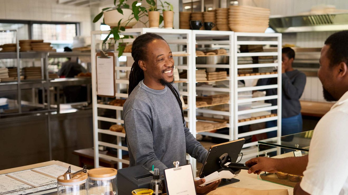 A bakery employee assists a customer at an artisan bakery using a tablet POS.