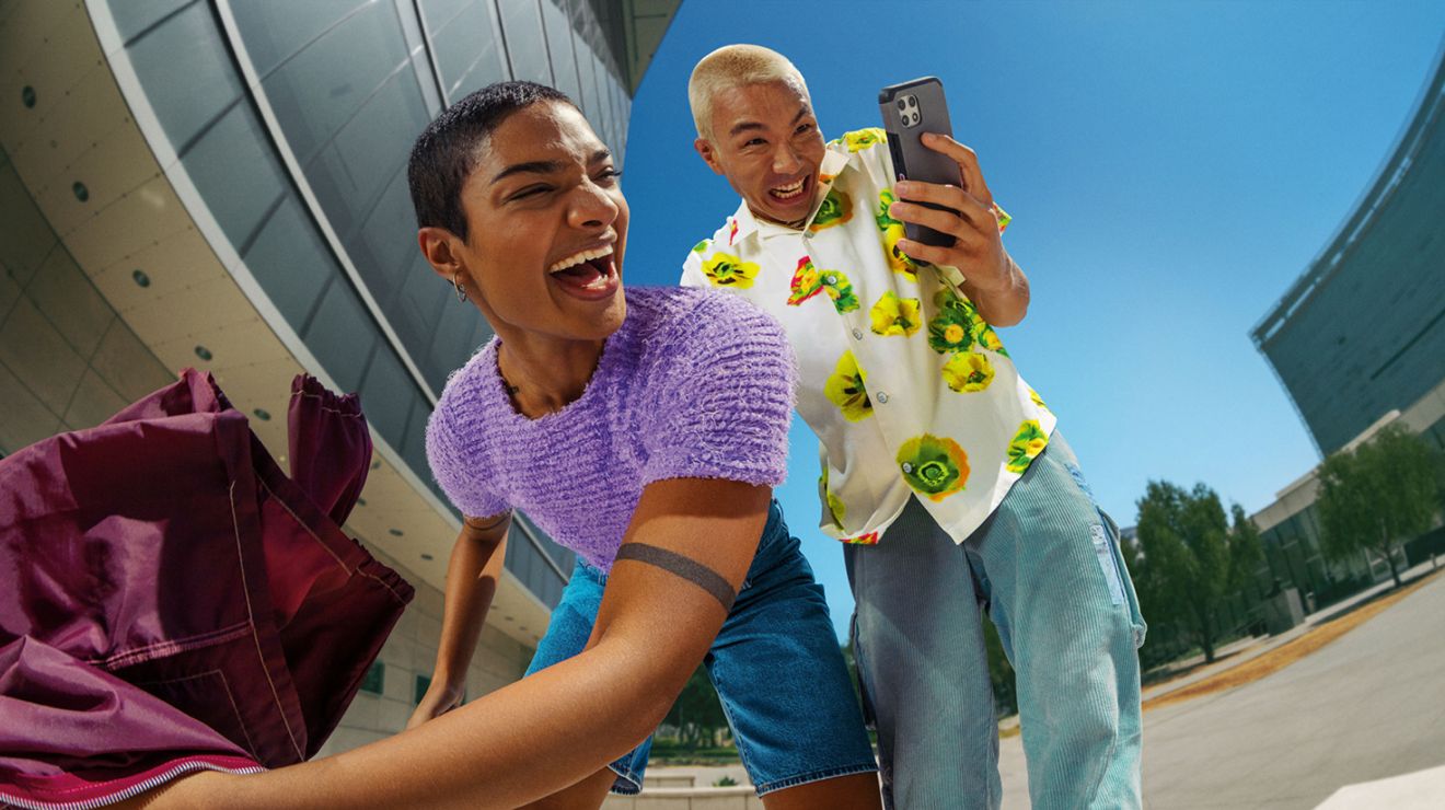 Group of friends smiling and taking a selfie outdoors with a smartphone.