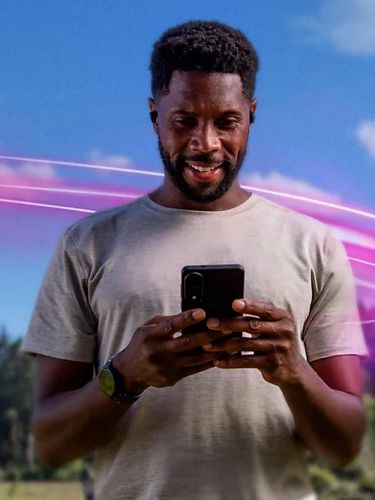 Man looking at a smartphone outside in a natural setting.
