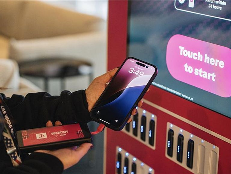 A person holding their phone up to a charging station. 