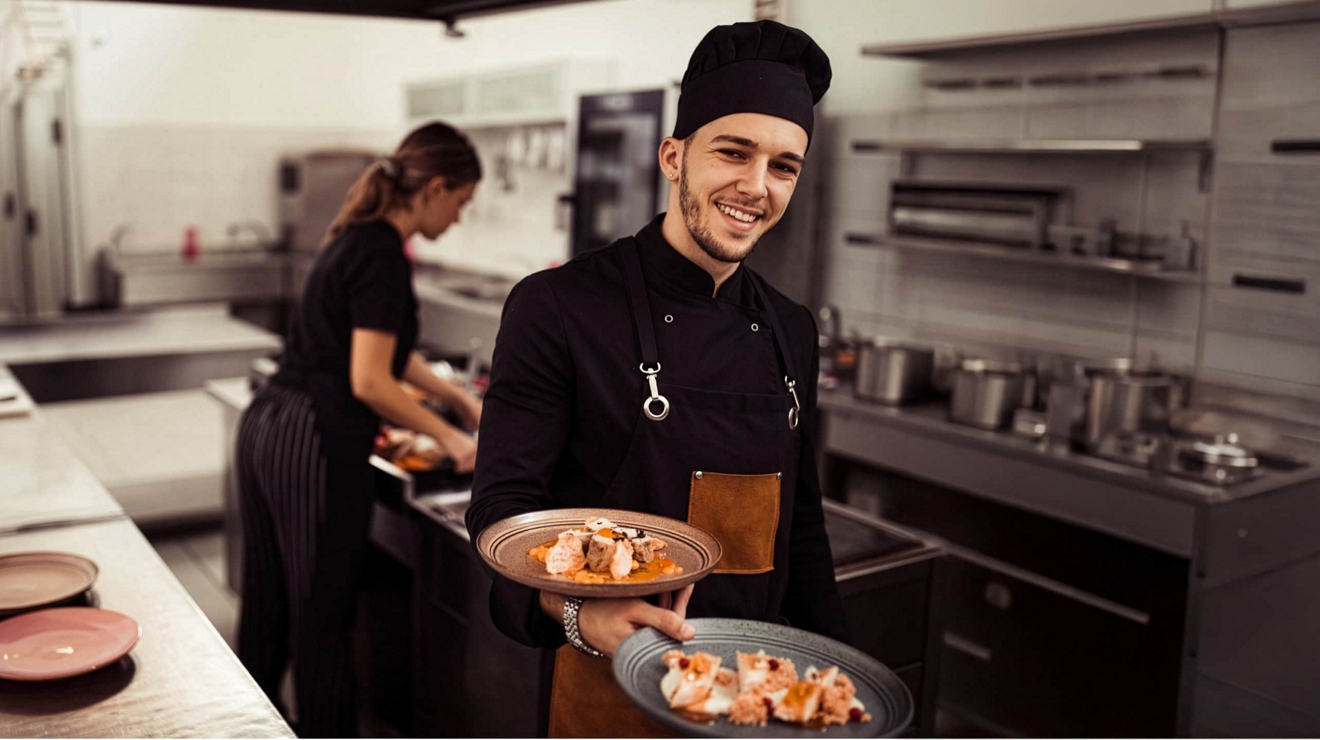 Two chefs prepare and plate food in a restaurant kitchen.