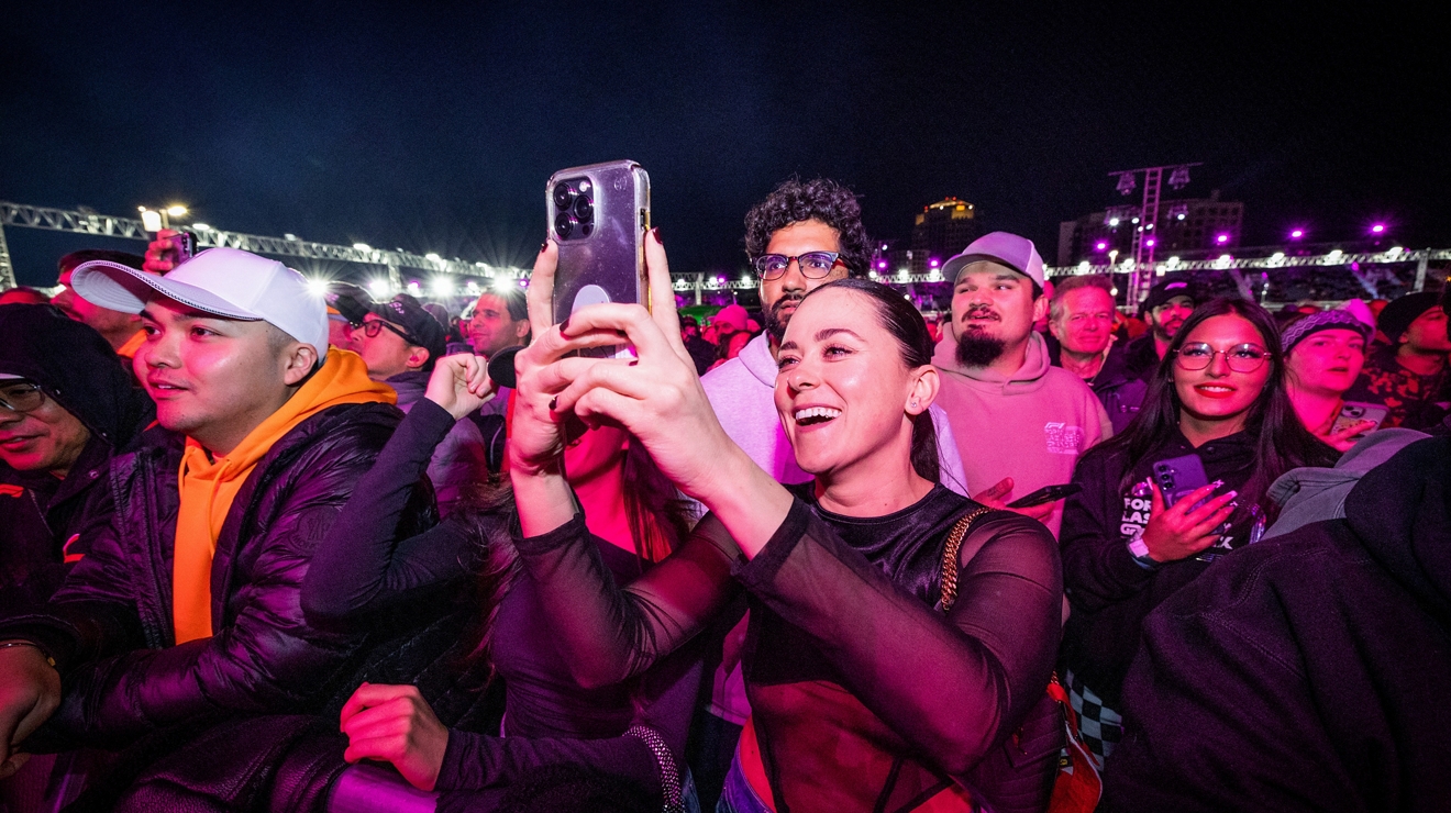 Crowd of concertgoers smiling and taking photos with their phones.
