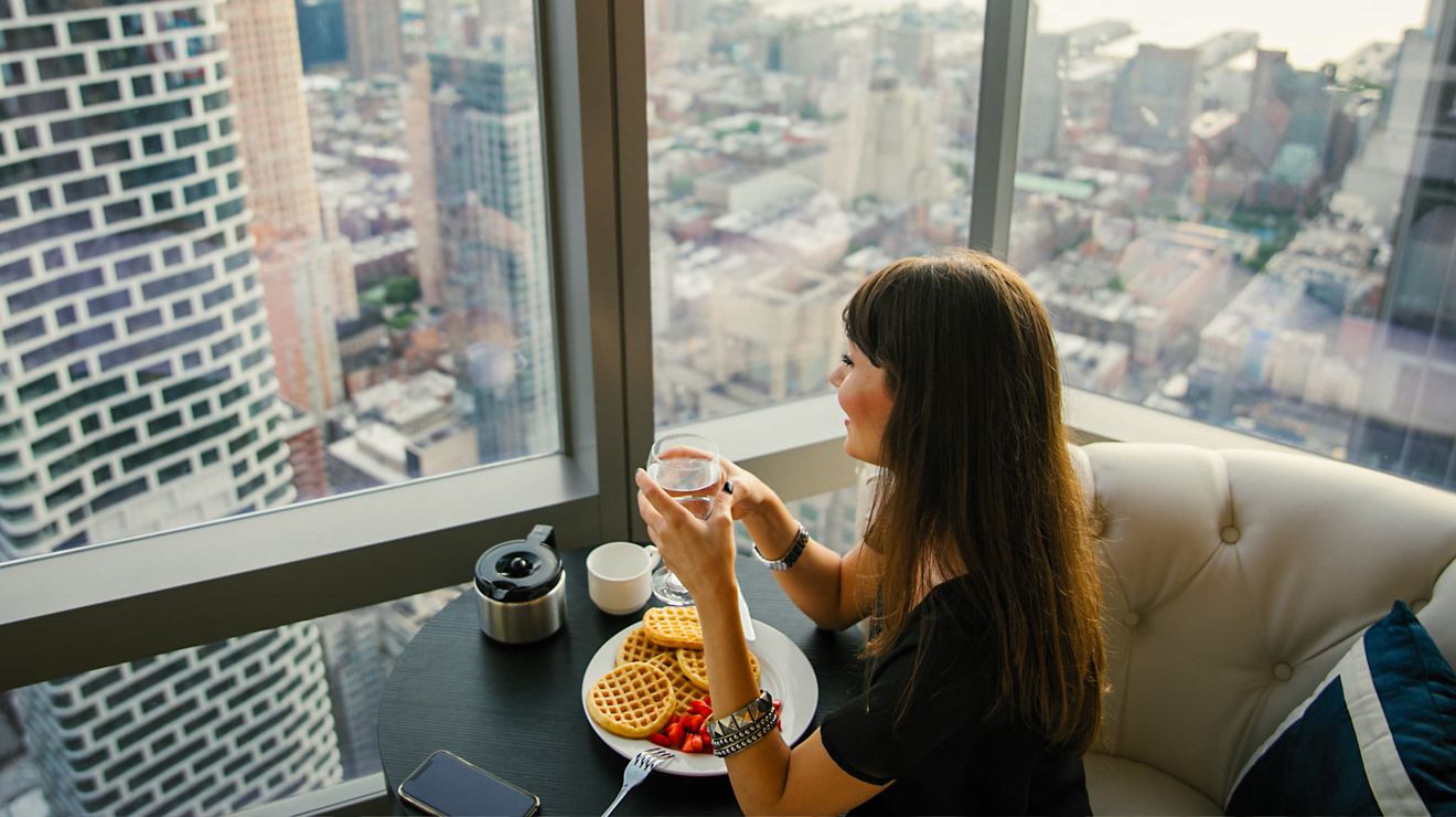 A T-Mobile customer enjoys lunch at a cafe with a city view.