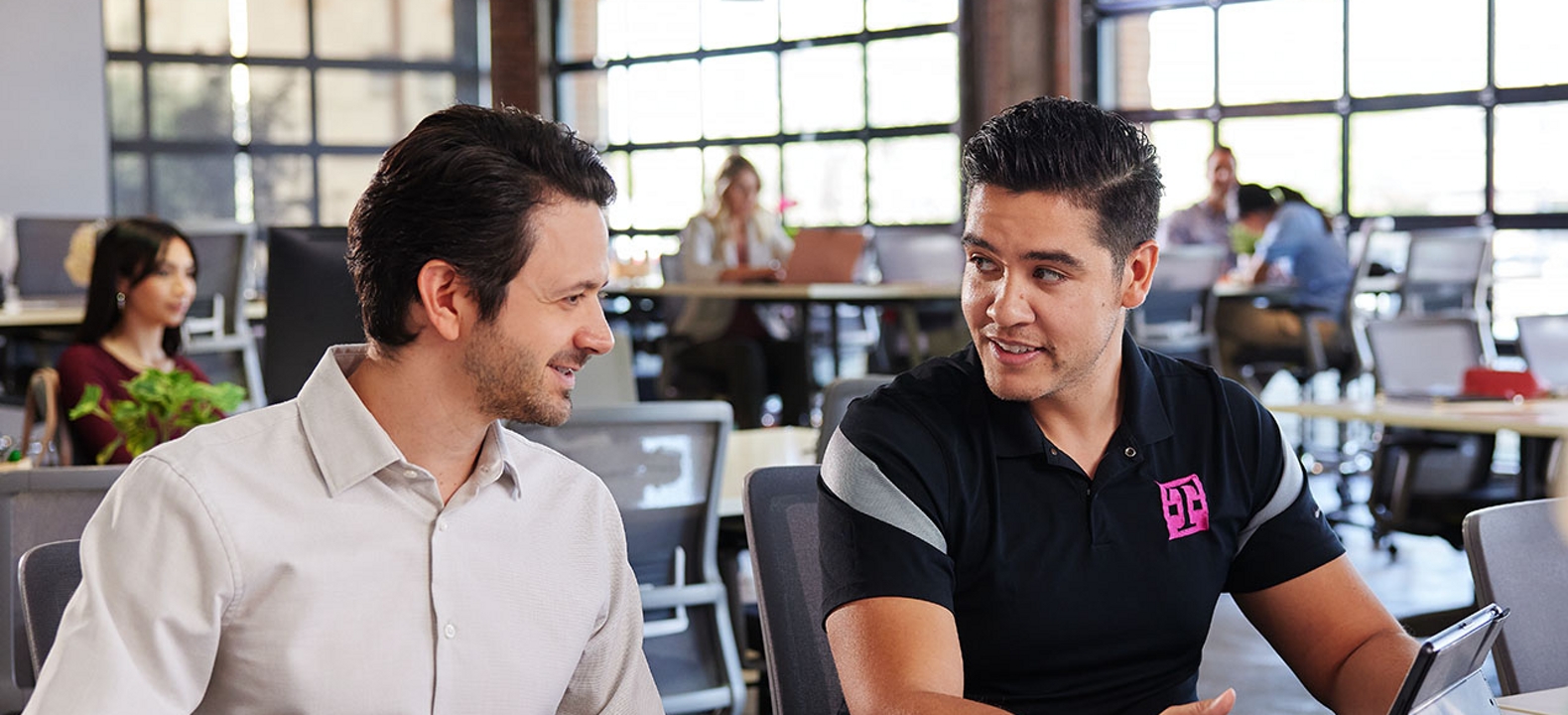 Two co-workers looking at a tablet in their company’s open workspace.