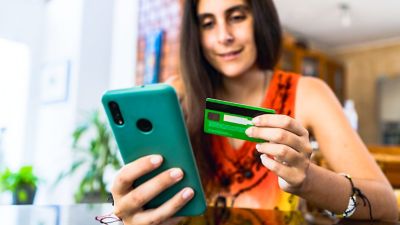 Woman uses credit card to make a purchase on her phone. 