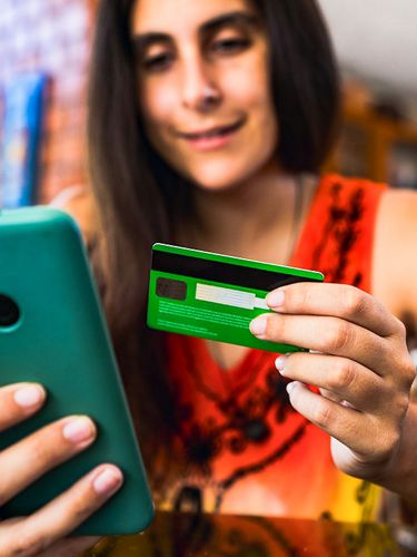 Woman uses credit card to make purchase on her phone. 