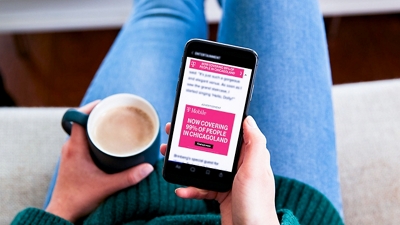 Customer holds phone showing a personalized T-Mobile ad in one hand and coffee in the other.