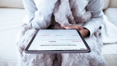 Woman relaxing in robe and looking at graphs on tablet.