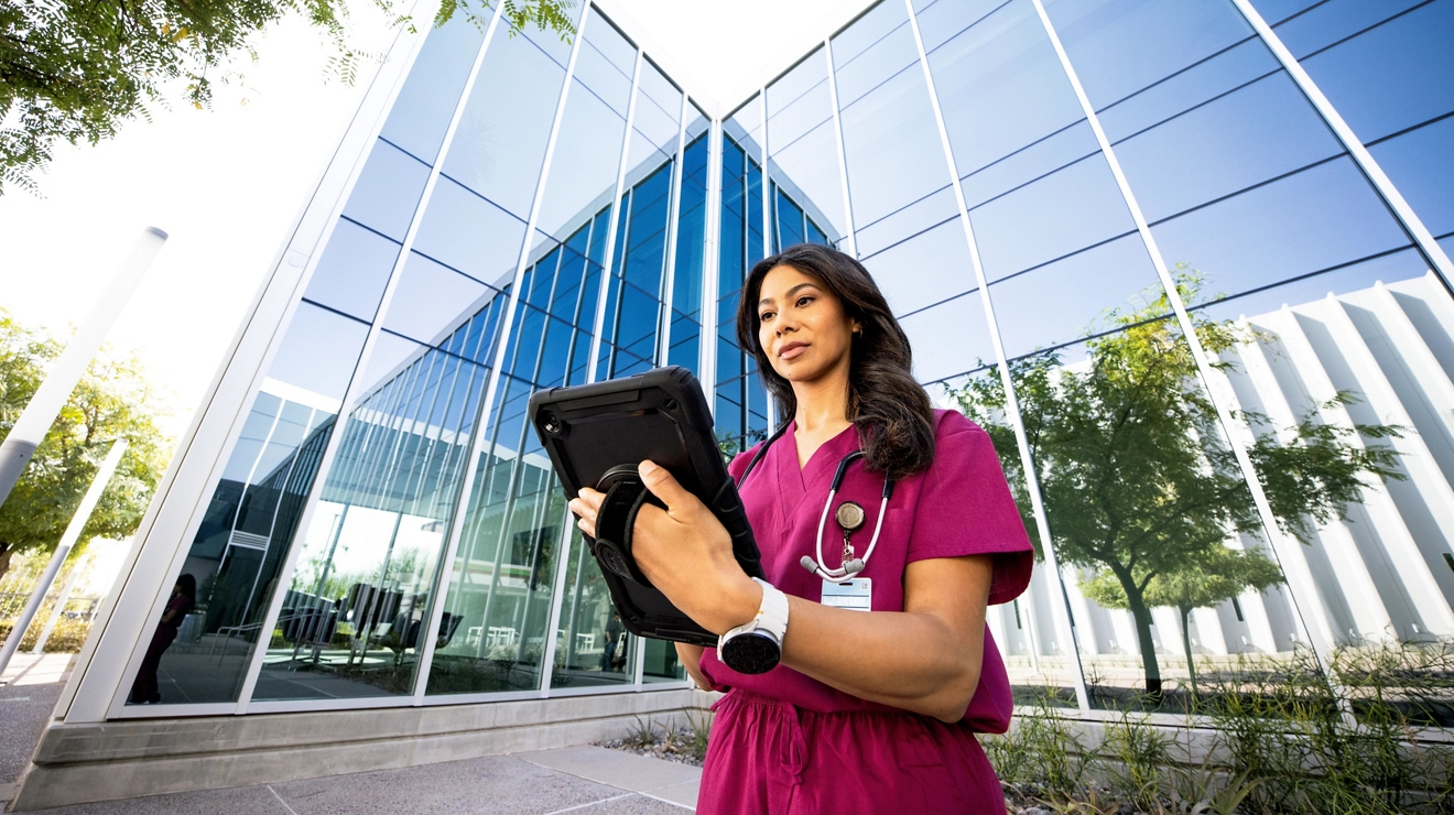 medical professional on tablet in front of building