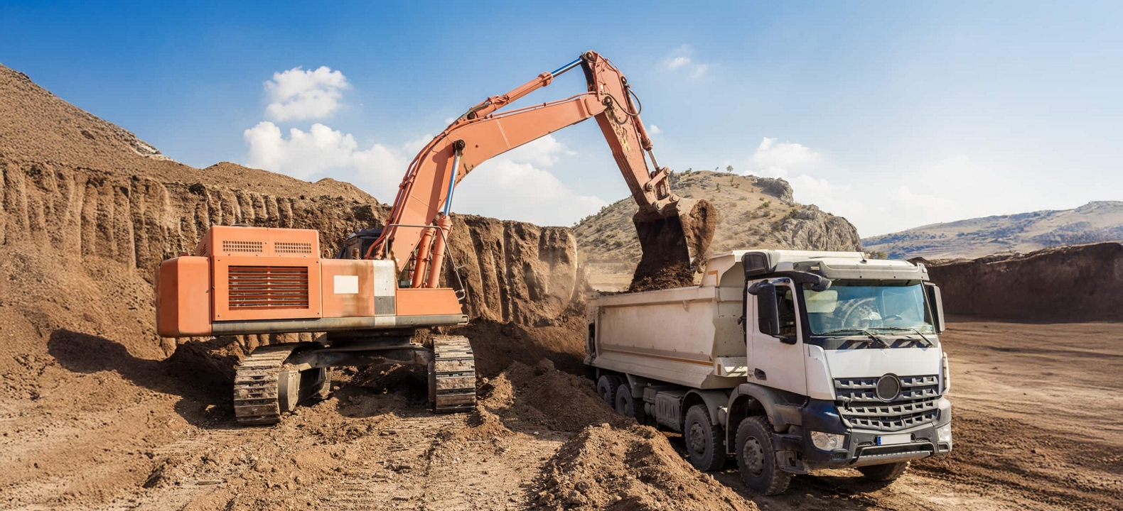Excavator loading a dump truck at a site monitored via GPS tracking.