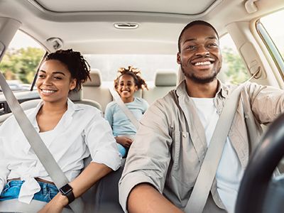 Una familia sonriendo mientras disfruta de un paseo en auto.