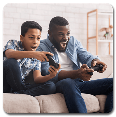 Father and son sitting in the living room couch while playing video games. 