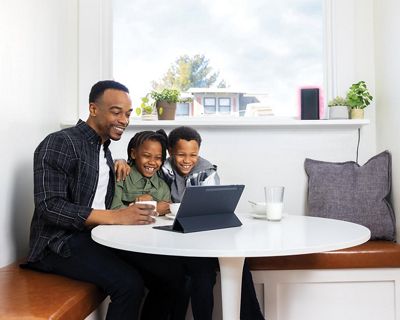 A man and two children sitting around a table with a laptop.