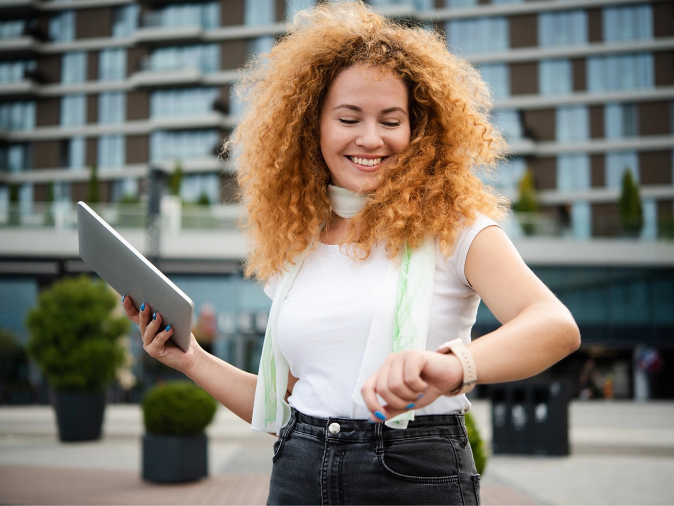 Woman outside with tablet checking her watch