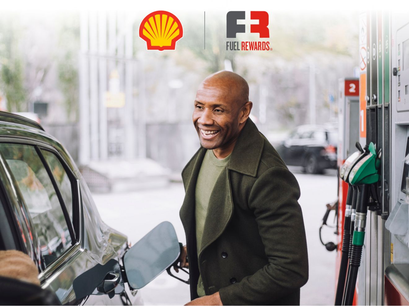 Person pumping gas at a Shell station while talking to family inside SUV.