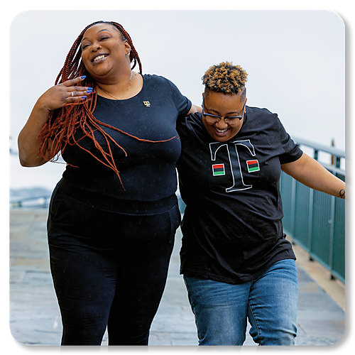 Two black women laughing and standing together.