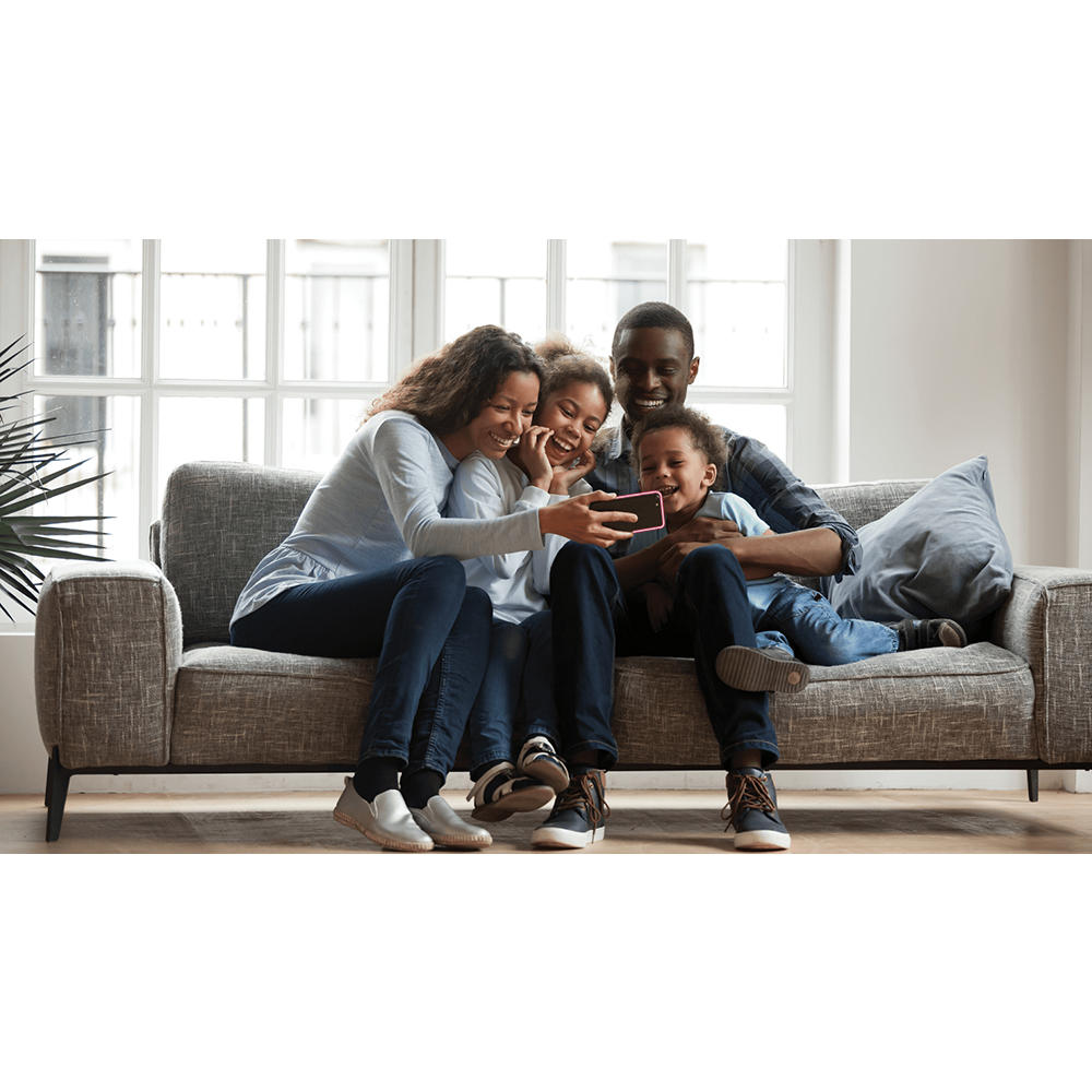 Family sitting on sofa gathered around a smartphone