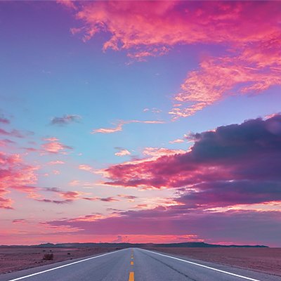 The AAA logo over an open road with a magenta-hued sunset in the distance