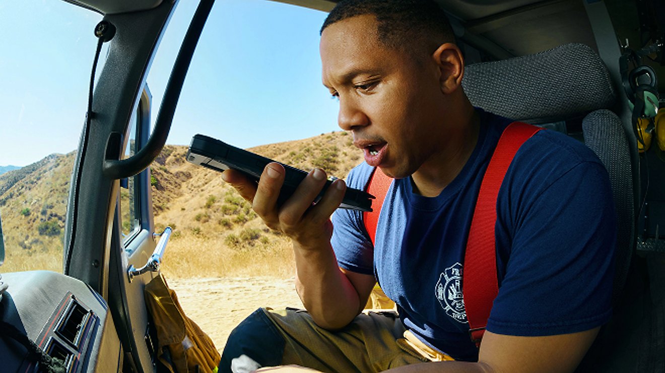 A firefighter in full gear talking on a phone