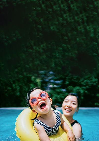 Mother and daughter playing with floaties in a pool.