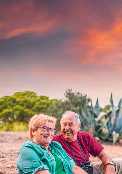 Older couple sitting on the beach in the tropics.