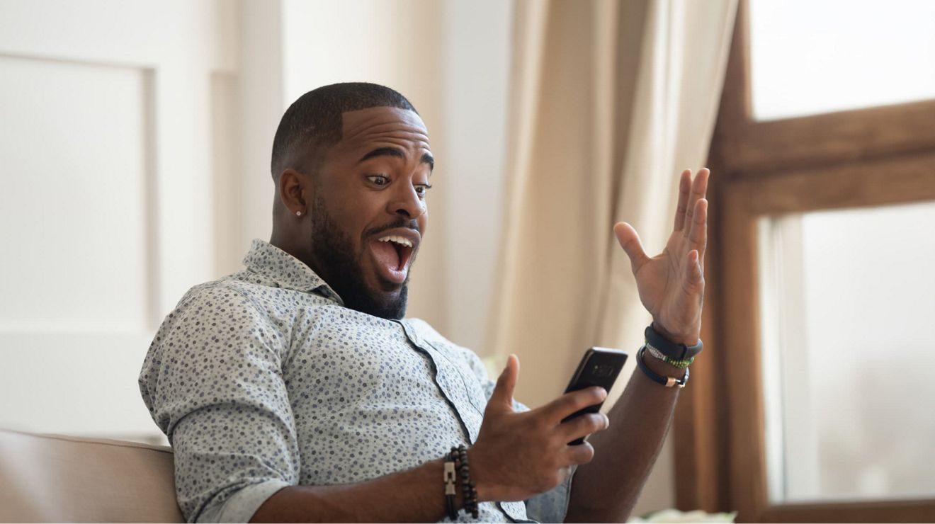 A T-Mobile customer on a smartphone excitedly reacts to learning about their wireless plan perks.