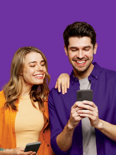 Un hombre y una mujer mirando su teléfono y sonriendo.